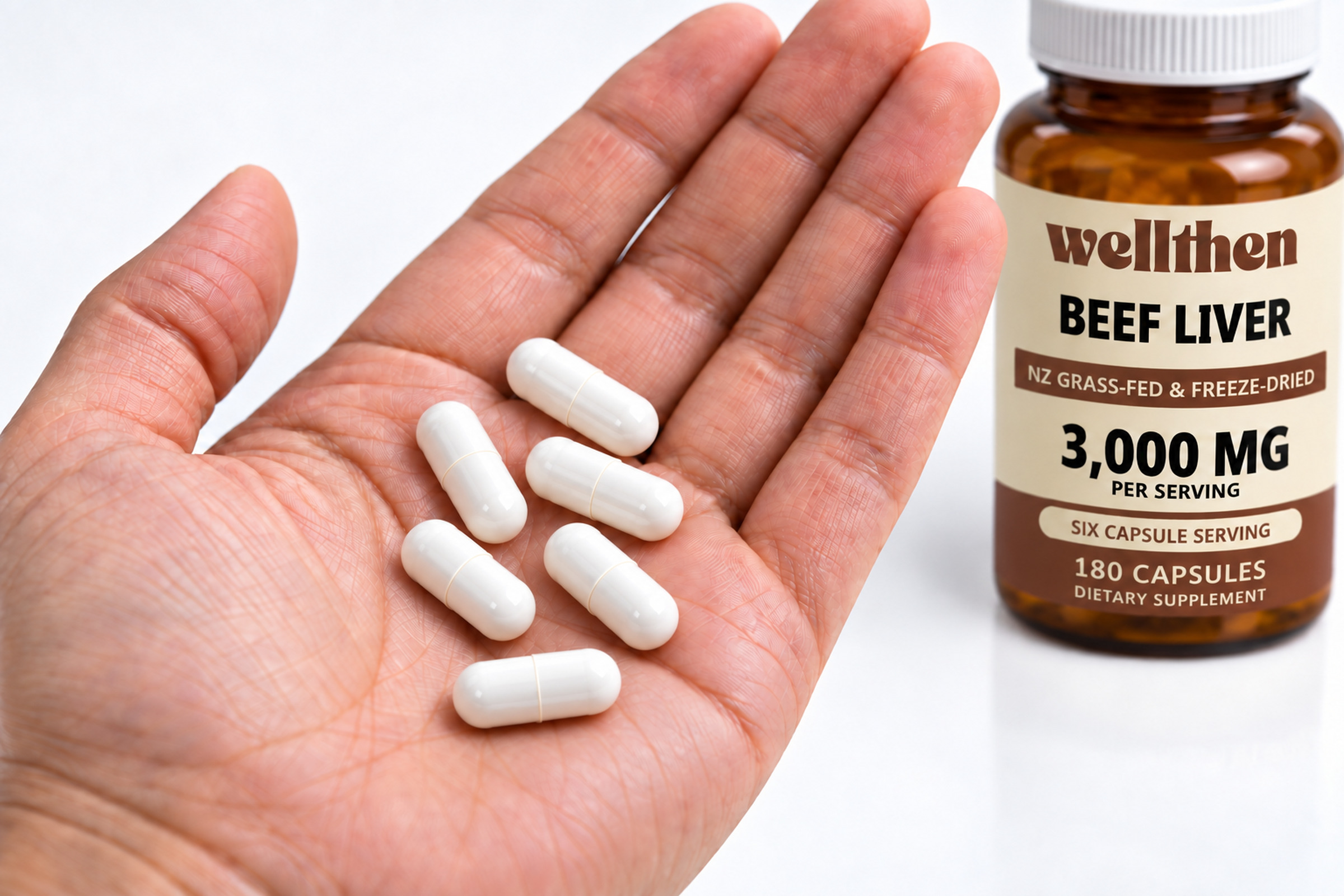 Six bovine organ capsules in a hand beside a finished beef liver bottle
